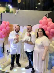 מוהל מומלץ דב קליין מחזיק תינוק לאחר טקס ברית מילה באולם בראשון לציון יחד עם ההורים המאושרים