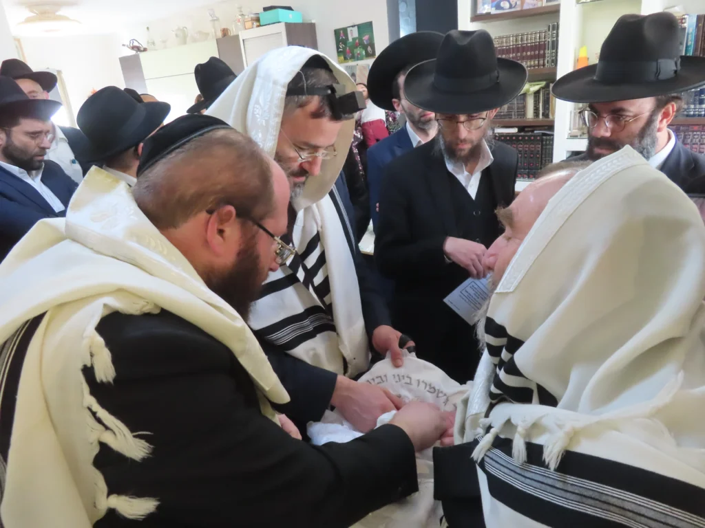 המוהל דב קליין עם אבא ותינוק בברית מילה עם תינוק רגוע