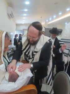 המוהל דב קליין בודק תינוק לפני ברית מילה ומודד את מוכנותו הרפואית